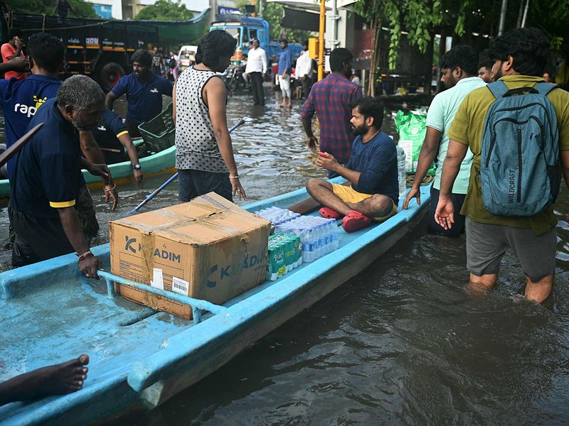 People wade along a flooded street in Chennai on December 5, 2023, following intense rains after Cyclone Michaung made a landfall. Chest-high water surged down the streets of India's southern city Chennai on December 5, with eight people killed in intense floods as Cyclone Michaung made landfall on the southeast coast.