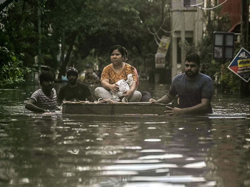 Volunteers evacuate a woman on a makeshift raft from a flooded area in Chennai on December 5, 2023, following intense rains after Cyclone Michaung made a landfall. Chest-high water surged down the streets of India's southern city Chennai on December 5, with eight people killed in intense floods as Cyclone Michaung made landfall on the southeast coast. (Photo by R__SATISH_BABU / AFP)
