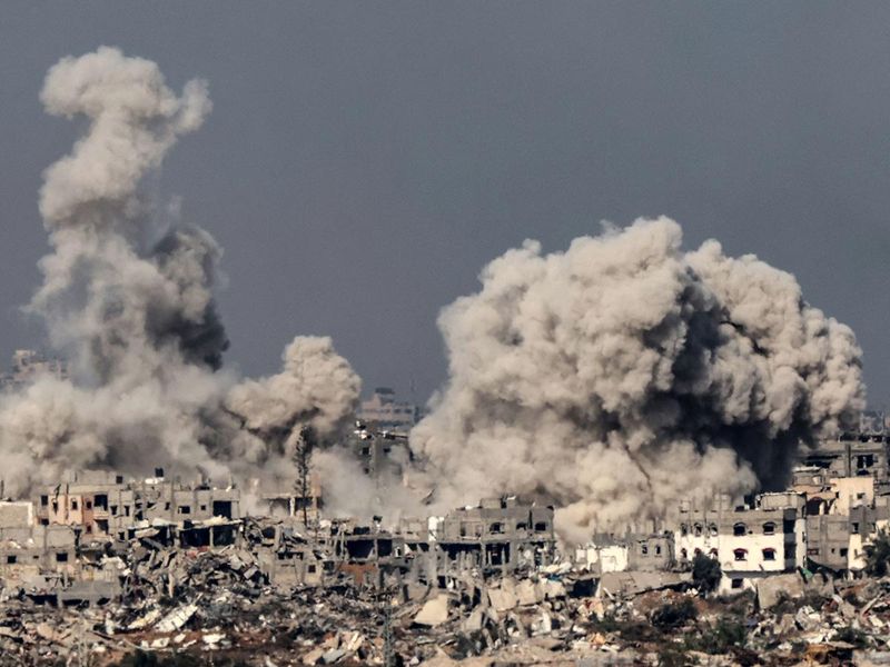 A picture taken from southern Israel near the border with the Gaza Strip on December 8, 2023, shows smoke rising above buildings during an Israeli strike in northern Gaza, amid continuing battles between Israel and the militant group Hamas. 