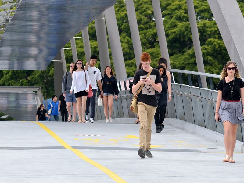 BRISBANE, AUS - SEP 25 2014:Australian students crossing on Goodwill foot bridge in Brisbane, Australia.It's a pedestrian and cyclist bridge which spans the Brisbane River in Brisbane, Australia.