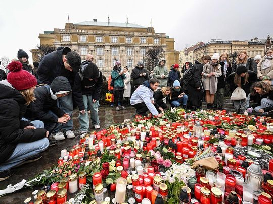 People places a candles and flowers at a makeshift memorial for the victims in front of the building of the Philosophical Faculty of the Charles University on December 22, 2023 in Prague, Czech Republic, one day after a mass shooting.  