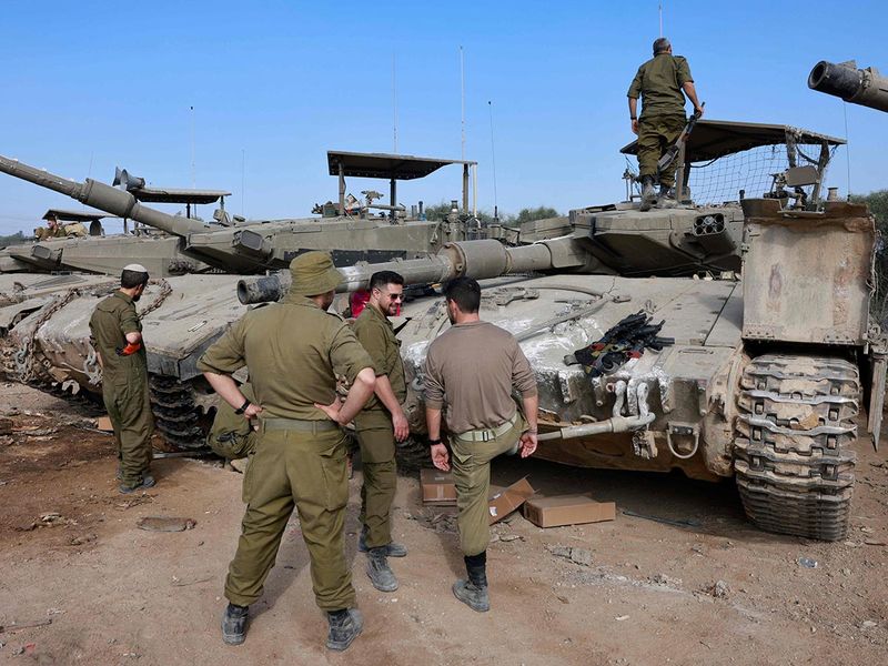 Israeli soldiers gather around tanks near the border with the Gaza Strip in southern Israel on December 25, 2023, amid ongoing battles between Israel and the militant group Hamas. 