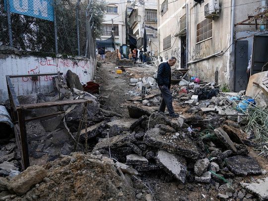 Palestinians walk through the aftermath of the Israeli military raid on Nur Shams refugee camp in the West Bank. 