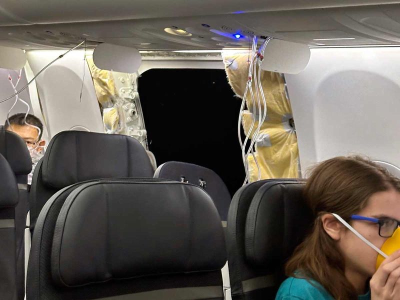 This image provided by Kelly Bartlett shows passengers near a hole in the fuselage of an Alaska Airlines Boeing 737 Max 9, Flight 1282, which was forced to return to Portland International Airport on Friday, Jan. 5, 2024. 