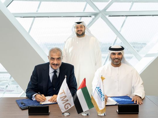 Hisham Talaat Moustafa (L) and Humaid Matar Al Dhaheri (R) sign agreement in the presence of H.E. Mohamed Hassan Alsuwaidi