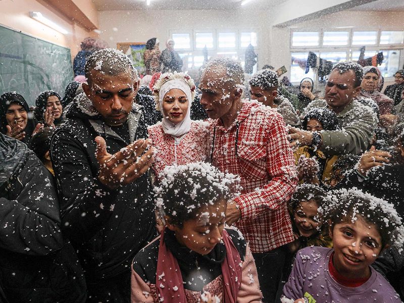 Palestinian bride Afnan Jibril (C), her father (2ndR) and her husband Mostafa Shamlakh (R) are covered with mousse during their wedding at the UNRWA School in the Al Salam neighbourhood of Rafah, southern Gaza Strip. 