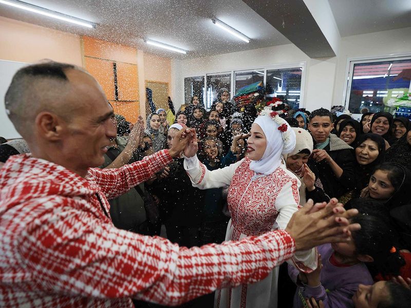 Palestinian bride Afnan Jibril (C) dances with her father 
