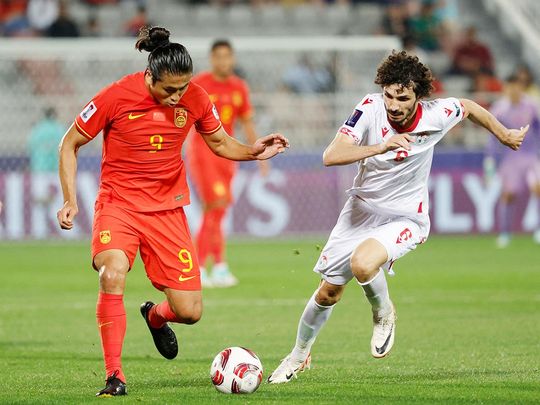 Tajikistan's defender Vakhdat Khanonov (right) vies for the ball against China's forward  Zhang Yuning