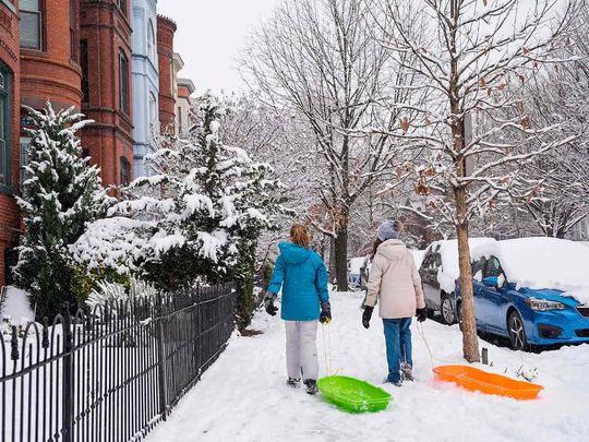 Girls walk through the Capitol Hill neighborhood dragging sleds, Friday, Jan. 19, 2024, as school was cancelled due to snow in Washington