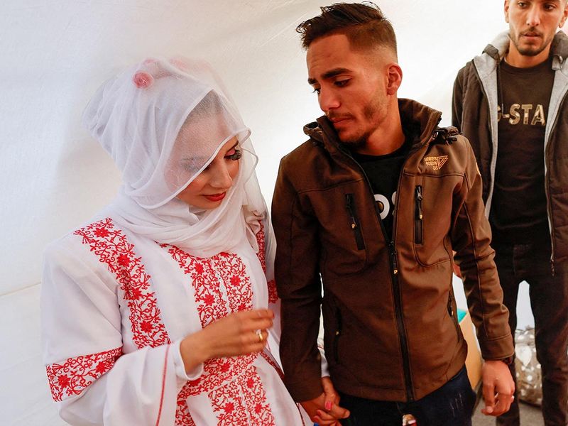 A Palestinian couple, Mohammed Al Ghandour and his bride Shahad, stands in a tent camp, on their wedding day, in Rafah in the southern Gaza Strip. 