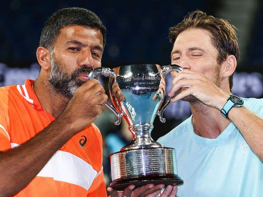 India's Rohan Bopanna (L) and Australia's Matthew Ebden celebrate with the trophy after victory against Italy's Simone Bolelli and Andrea Vavassori during their men's doubles final match on day 14 of the Australian Open tennis tournament in Melbourne on January 27, 2024.