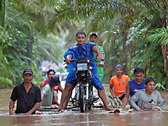 Residents push a makeshift raft loaded with a motorcycle through floodwaters brought about by heavy rains in Propseridad town, Agusan del Sur province on southern Mindanao island on February 1, 2024