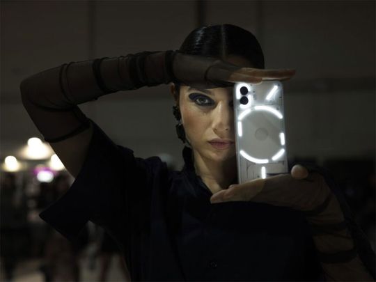A model showcases the Nothing's flagship smartphone Phone (2) during the Dubai Fashion Week.