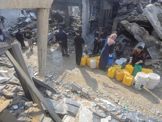 Palestinians gather to collect water from a house destroyed by an Israeli strike, in Jabalia refugee camp in the northern Gaza Strip on February 7, 2024. 