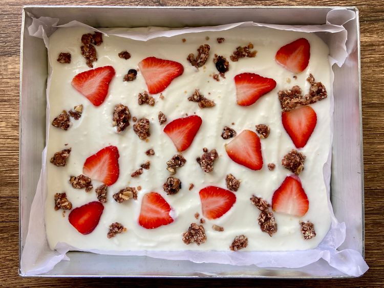 Line a baking tray with parchment paper. Mix yoghurt with stevia and vanilla extract, spread it evenly on the tray and top with sliced strawberries.