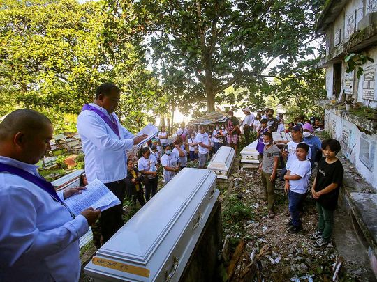 Catholic lay ministers say a prayer during the mass burial of victims of the Masara landslide, at Mawab, Davao de Oro, Philippines. 