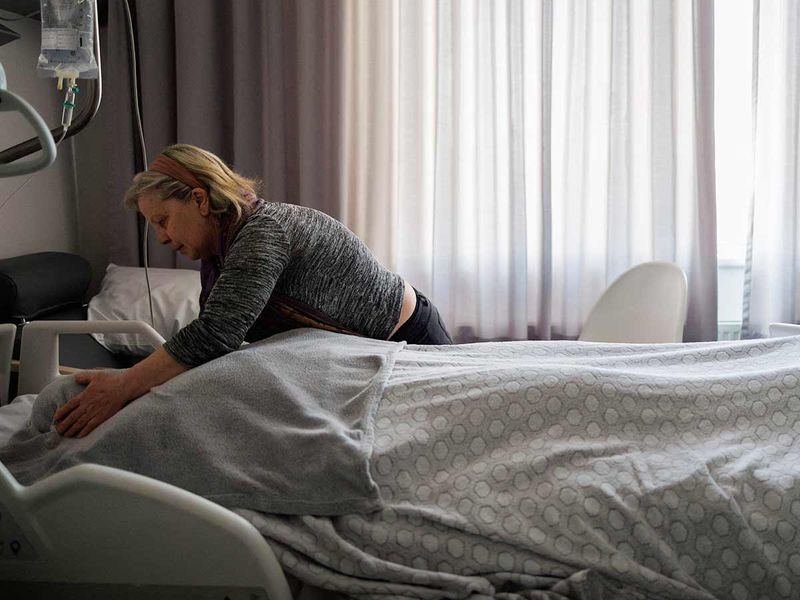 Carer Marie-Josee Rousseaux adjusts the blanket on Lydie Imhoff's body following the euthanasia process at a hospital in Belgium, on February 1, 2024. 