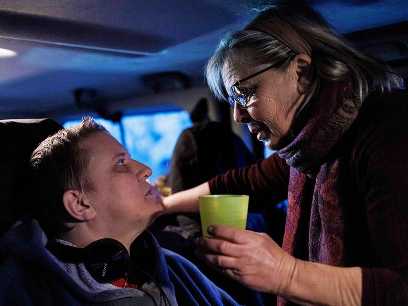 Carer Marie-Josee Rousseaux gives water to Lydie Imhoff in the van during an early departure from Besançon, to Belgium on January 31, 2024.  
