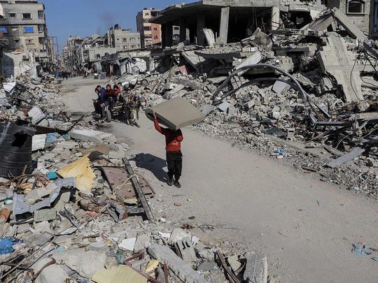 Palestinians walk past destroyed houses, in Jabalia refugee camp, in the northern Gaza Strip on February 22, 2024. 