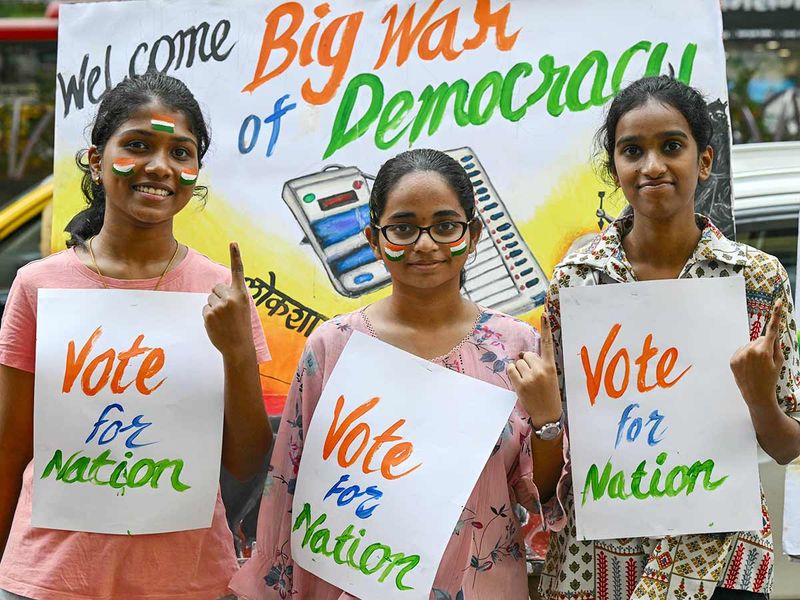 Art school students pose with posters illustrating the upcoming India's parliamentary elections, in Mumbai on March 16, 2024.  