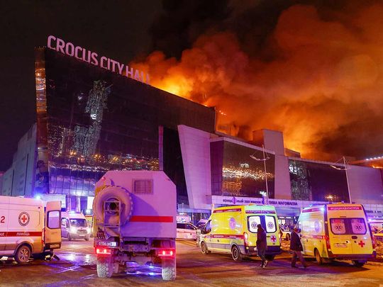 Vehicles of Russian emergency services are parked near the burning Crocus City Hall concert venue following a reported shooting incident, outside Moscow, on March 22, 2024. 
