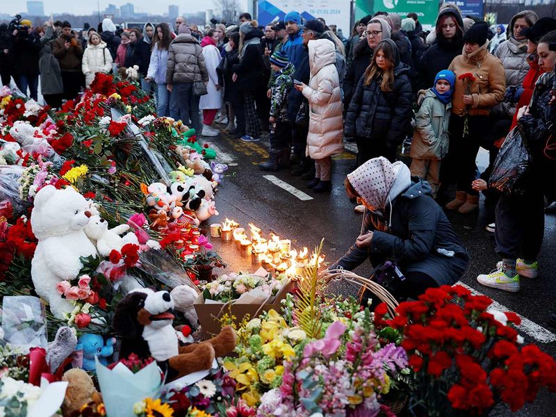 People gather at a makeshift memorial to the victims of a shooting attack set up outside the Crocus City Hall concert venue outside Moscow, on March 23, 2024. 