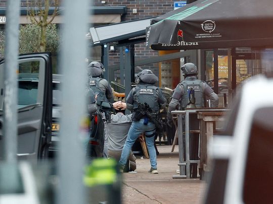 Dutch police officers detain a person near the Cafe Petticoat, where several people are being held hostage in Ede, Netherlands March 30, 2024.  