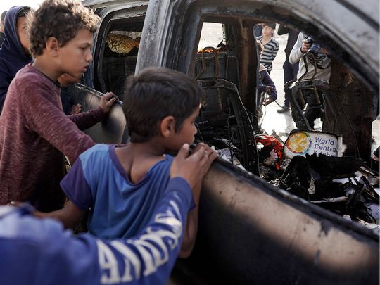 People gather around the carcass of a car used by US-based aid group World Central Kitchen, that was hit by an Israeli strike the previous day in Deir Al Balah in the central Gaza Strip on April 2, 2024. 