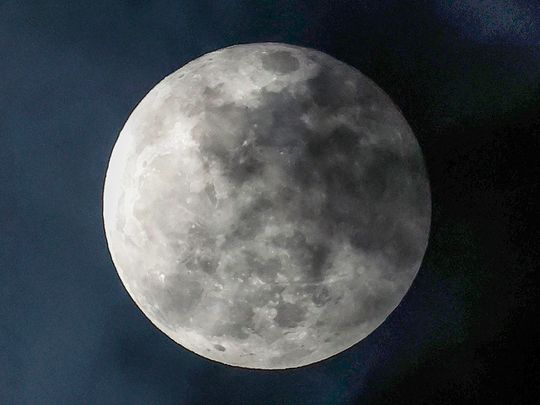 Cloud cover shades the full 'Worm moon' as it rises above Qatar's capital Doha