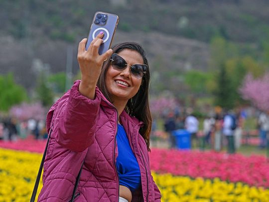 A tourist takes a selfie with a mobile phone at the Indira Gandhi Memorial Tulip Garden in Srinagar, on April 3, 2024. 