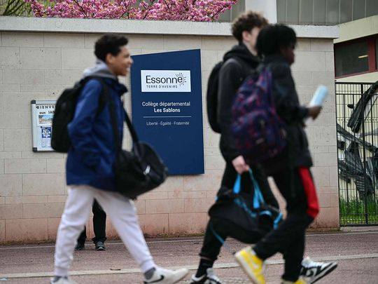 Middle schoolers walk by an indicative panel reading 'Departmental middle school - Les Sablons' at the entrance of the school Les Sablons in Viry-Chatillon on April 5, 2024, a day after a teenage boy was assaulted and rushed to the hospital.  