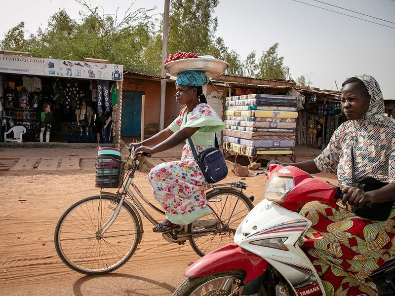 Jacqueline Taonsaon balances a plate of strawberries on her head as she rides on her bicycle to the market in Ouagadougou. 