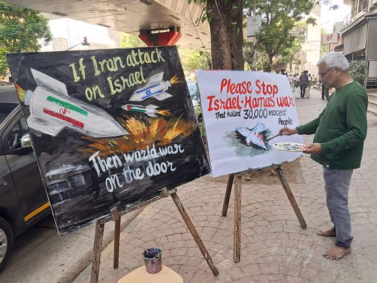 An artist paints along a street in Mumbai on April 13, 2024, to depict the unrest between Palestine, Israel and Iran. 