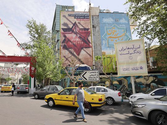 Iranians walk next to an anti-Israel poster in Tehran on April 13, 2024. 
