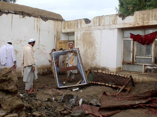 A man removes a window frame inside the debris of a damaged house following a flash flood in Gulgad village in Lal Pur district of Nangarhar province, Afghanistan, April 15, 2024.