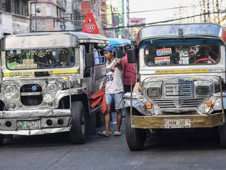 In this photo taken on April 5, 2024, a 'barker' (C), a person who calls passengers to ride jeepneys, guides drivers along a street in Manila.