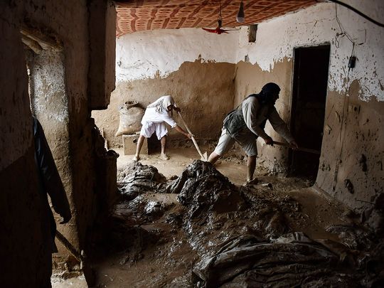 Afghan men shovel mud from a house