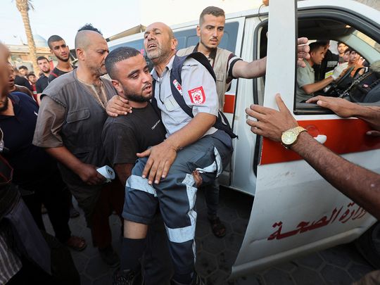 A man carries a Paramedic, who was wounded in an Israeli strike, in Deir Al-Balah