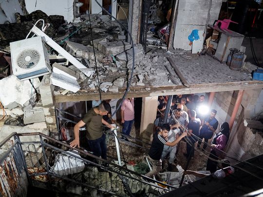 People walk in a damaged building targeted by Israeli forces