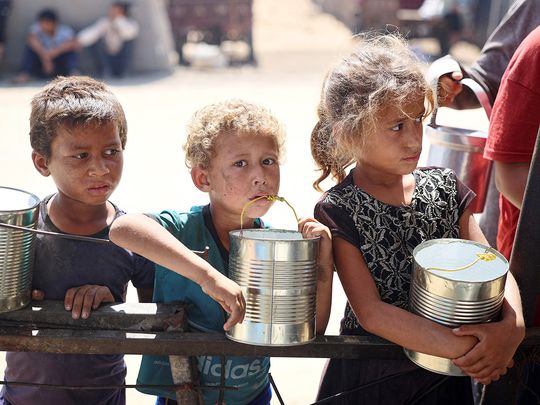 Children wait for food being distributed at a camp for internally displaced people
