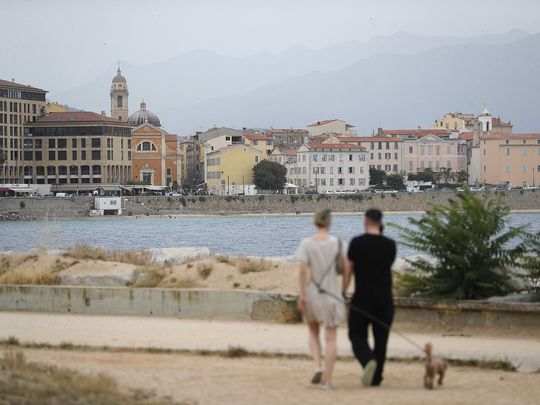 A couple walk along the seafront in Ajaccio, on the French Mediterranean island of Corsica