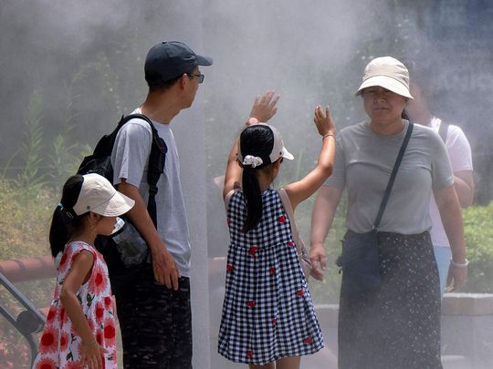 A family cools down under a mist shower during hot weather in central Tokyo