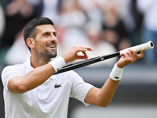 Serbia's Novak Djokovic imitates playing the violin 