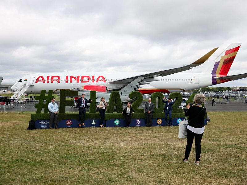 Attendees taking a photograph near an Airbus SE A350-900 passenger aircraft, operated by Air India Ltd., during the opening day of the Farnborough International Airshow in Farnborough, UK, on Monday, July 22, 2024. The aviation summit is typically a platform for planemakers to rack up multibillion-dollar deals. 