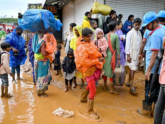 Tea plantation workers with their belongings, head to a relief camp after landslides in Wayanad on July 31, 2024. 