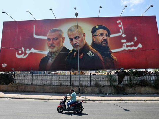 A man rides his moped past a billboard bearing portraits of slain leaders