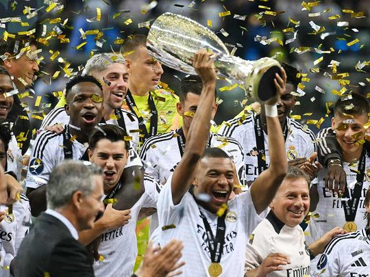 Real Madrid's French forward Kylian Mbappe celebrates with the trophy