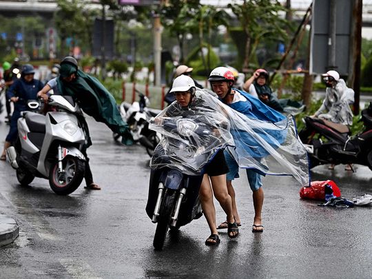 Motorcyclists struggle from the strong wind of Typhoon Yagi in Hai Phong city 