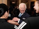 Britain's King Charles III reacts as he is hugged by members of New Zealand's Black Ferns rugby union team