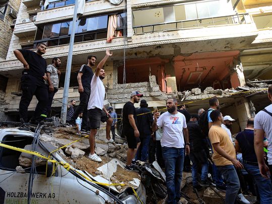 People gather in front of a building targeted by an Israeli strike